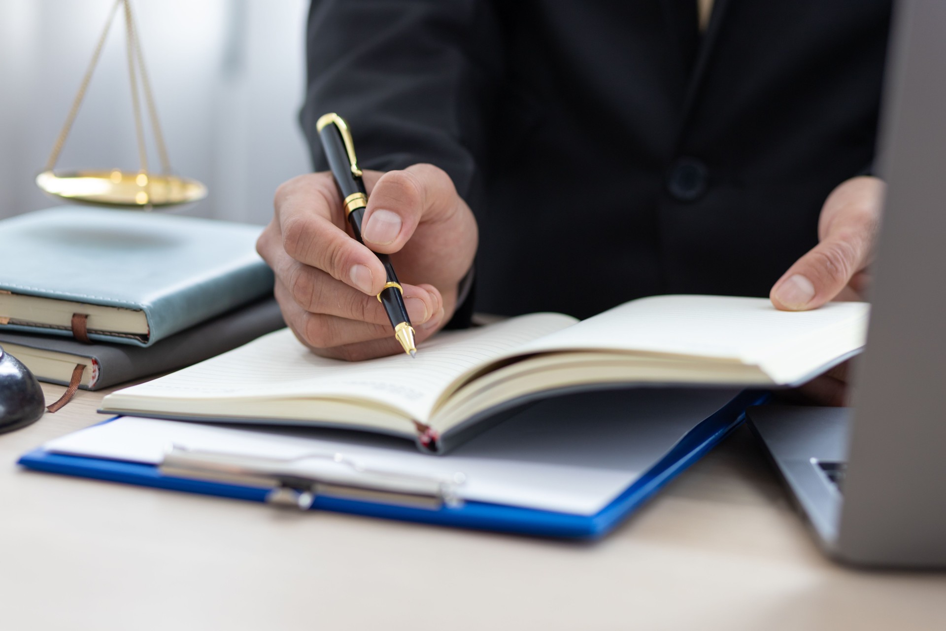 El asesor legal está escribiendo una nota en un bloc de notas mientras trabaja en la oficina de un abogado.